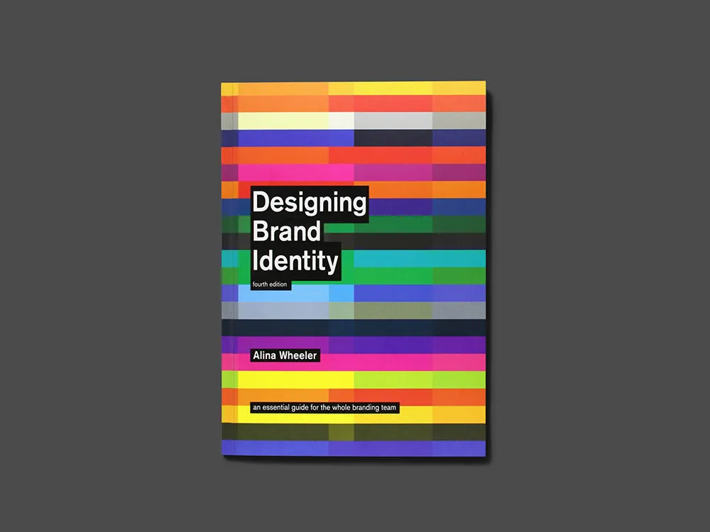 The image shows the cover of the book "Designing Brand Identity" by Alina Wheeler, fourth edition. The cover features colorful horizontal stripes in various shades of red, orange, yellow, green, blue, and purple, with the title and author's name in white