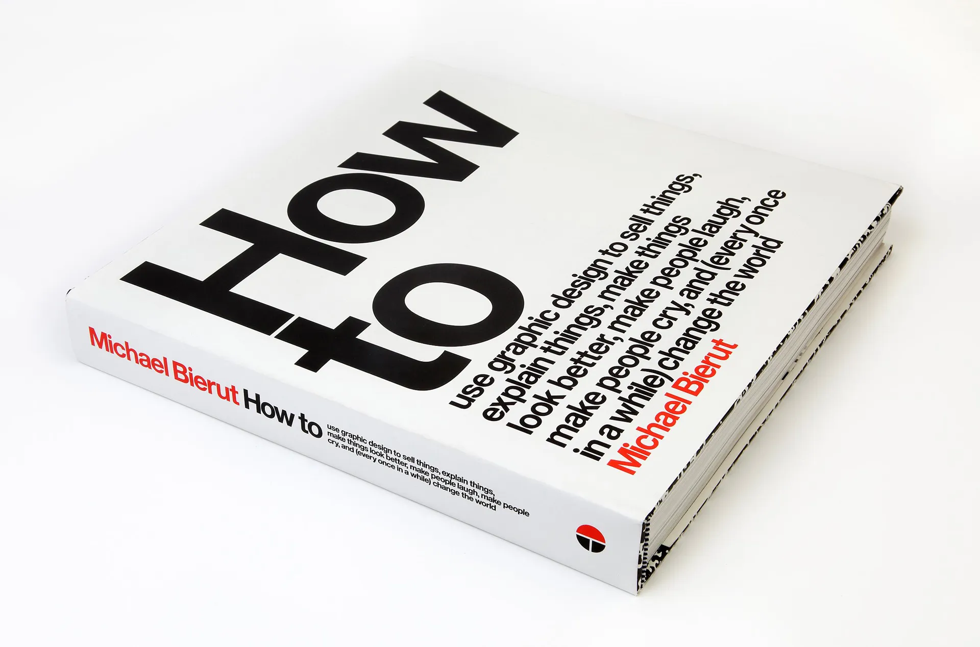 A book titled "How to" by Michael Bierut. The cover features bold black and red text that extends across the front and spine. The book is positioned at an angle, showing both the cover and the spine which emphasizes its title and author's name.