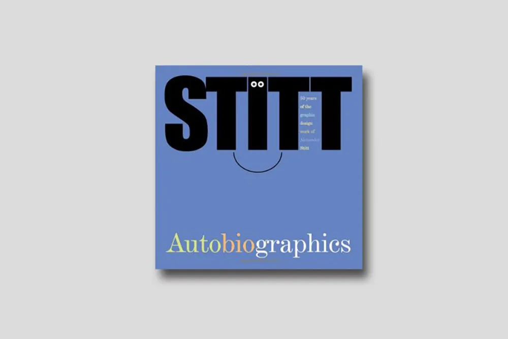 A blue book cover with bold black text at the top spelling "STITT" with two eyes forming the 'i's and a curved line forming a smile. Below, in smaller, colorful text, it reads "Autobiographics." At the top right, it says, "30 years of the people's design